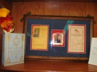 Koa framed Historical items:  Cornerstone Day program,  Washington Place commemorative ornament with Queen Lili`uokalani portrait,  Flag Raising Day program